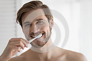 Head shot portrait smiling young man brushing teeth, oral hygiene