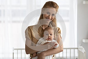 Head shot portrait of smiling young mother holding baby