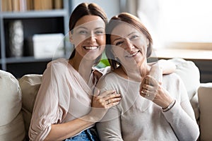 Head shot portrait smiling young woman hugging mature mother