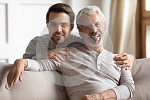 Head shot portrait young man embracing sitting on couch dad.