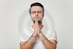 Head shot praying man isolated on grey studio background portrait.