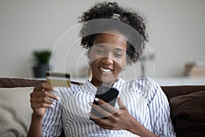 Head shot smiling African American woman using smartphone, paying online