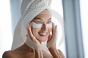 Head shot smiling beautiful woman applying hydrogel eye patches