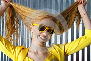 Head shot of smiling blond woman in sunglasses playing with hair