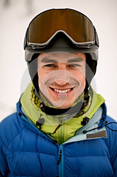 Head shot of smiling man skier wearing ski helmet with goggles