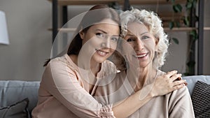 Head shot smiling young woman with elderly mother hugging