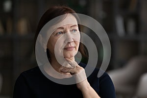 Head shot thoughtful melancholic mature woman looking to aside