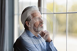 Head shot thoughtful upset mature man looking out window