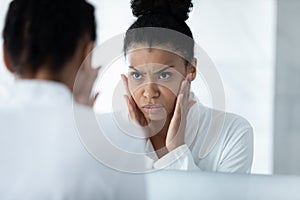 Head shot unhappy African American young woman checking skin