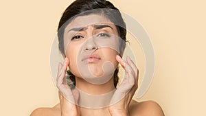 Head shot unhappy Indian female touching skin, worried about blemishes photo