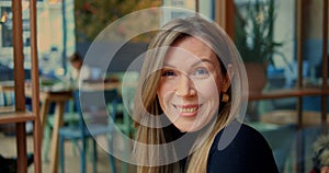 Head shot woman raise eyebrows smile openly in urban cafe with genuine interior