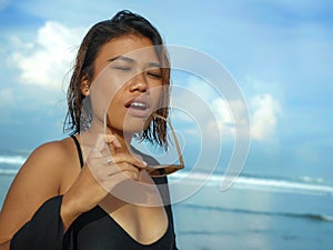 Head and shoulders lifestyle portrait of young beautiful and sexy Asian girl in bikini and sunglasses enjoying holidays at