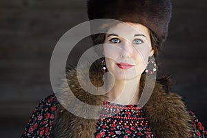 Head and shoulders portrait of Russian beauty with blue eyes wearing fur Cossack hat