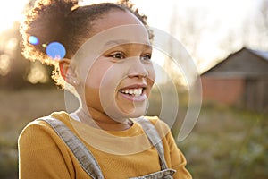 Head And Shoulders Portrait Of Smiling Girl Outdoors In Countryside With Flaring Evening Sun