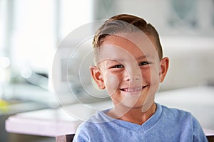 Head And Shoulders Portrait Of Smiling Hispanic Boy At Home