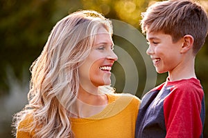 Head And Shoulders Portrait Of Smiling Mother And Son Hugging Outdoors