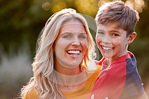 Head And Shoulders Portrait Of Smiling Mother And Son Hugging Outdoors