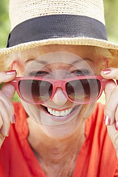 Head And Shoulders Portrait Of Smiling Senior Woman Wearing Sunglasses