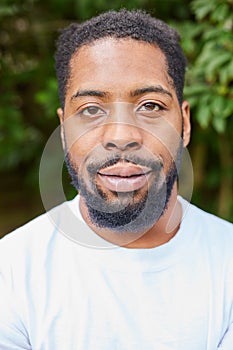 Head And Shoulders Portrait Of Smiling Young Man Standing Outdoors In Garden