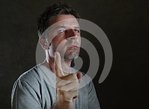 Head and shoulders portrait of young attractive serious and upset man warning and raising his finger as giving advise or