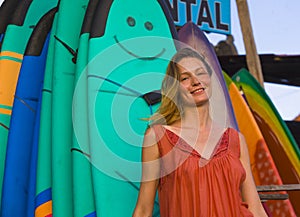 Head and shoulders portrait of young beautiful and happy blond woman smiling relaxed and cheerful posing with colorful surf boards