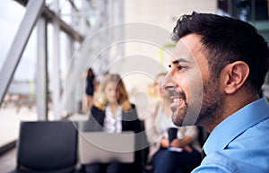 Head And Shoulders Shot Of Businessman Sitting In Airport Departure Lounge