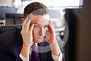 Head and shoulders of a young stressed businessman, head in hands