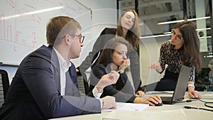 Head and staff brainstorm in front of laptop in conference room.