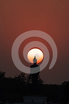 Head of statue of Buddha image surrounded by sun during sunset