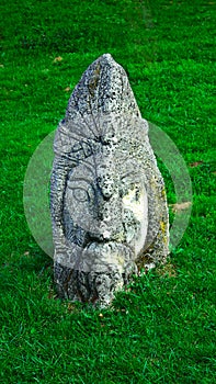 Head of a stone idol, on a forest lawn, pagan god