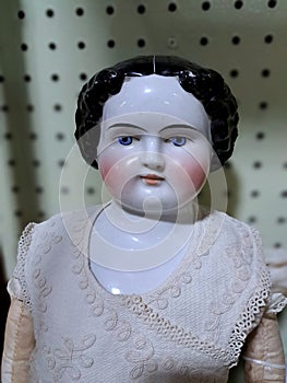 Head and Torso of an Antique Porcelain Doll with blue eyes, rosy cheeks, and black hair