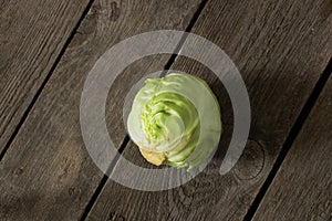 A head of young green cabbage lies on a wooden board