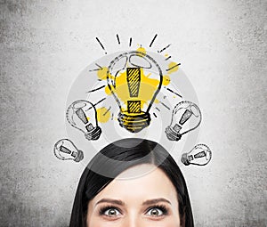 A head of young lady who is thinking about new business ideas. A light bulb are drawn on the concrete wall.