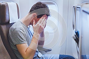 Headache in the airplane, man passenger afraid and feeling bad during the flight in plane