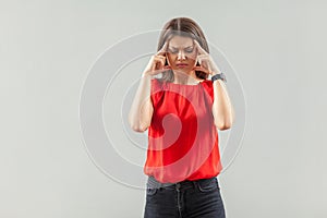 Headache, confution or thinking. Portrait of serious beautiful brunette young woman in red shirt standing and holding her painful