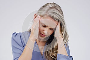 This headache is driving me crazy. Shot of a young woman holding her head while suffering from a headache against a grey