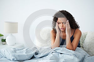 Is this headache ever going to leave. an attractive young woman suffering from a headache and rubbing her head while in