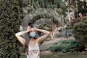 Headache girl in blue medical mask. Woman touches her head because sicks coronavirus covid-19. Attractive girl weared