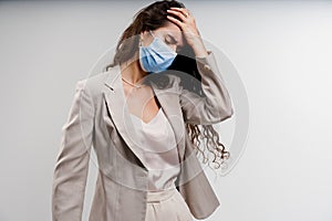 Headache girl in blue medical mask. Woman touches her head because sicks coronavirus covid-19. Attractive girl weared photo