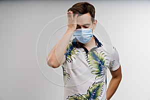 Headache man in blue medical mask isolated white background. Man touches her head because sicks coronavirus covid-19
