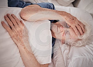 Headache, pain and senior woman in bed for trauma recovery, rehabilitation or rest in elderly care nursing home
