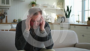 Headache pain. Unhappy middle aged senior man suffering from headache sick rubbing temples at home. Mature old senior