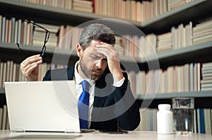 Headache, tiredness and stress. Man in suit uses a laptop, is tired got headache migraine. Headache pain concept