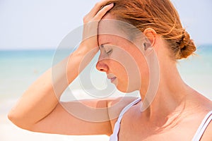 Headache woman on sunny beach. Woman with sunstroke. Hot sun danger. Health problem on holiday.