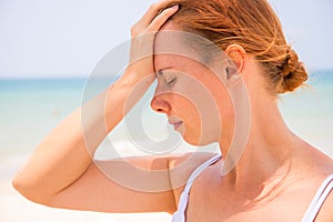 Headache woman on sunny beach. Woman with sunstroke. Hot sun danger. Health problem on holiday. photo