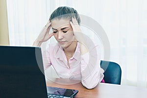 Headache in the workplace from restarting work. Stress at work. The girl holds her head from fatigue and headache.