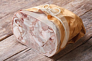 Headcheese closeup on table tied with twine and wrapped in paper