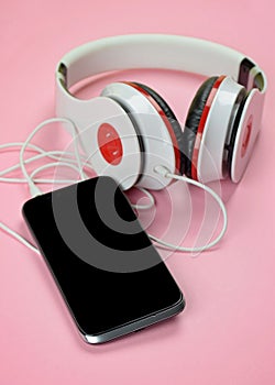 Headfones and smartphone on pink background.