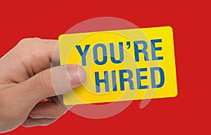 Headhunter showing card with phrase YOU`RE HIRED on red background, collage