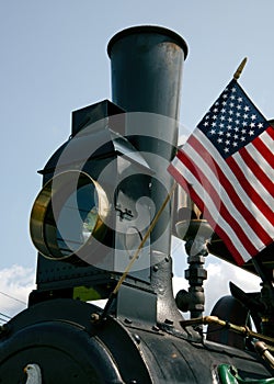 Headlamp and smokestack along with the American flag on an antique steam tractor